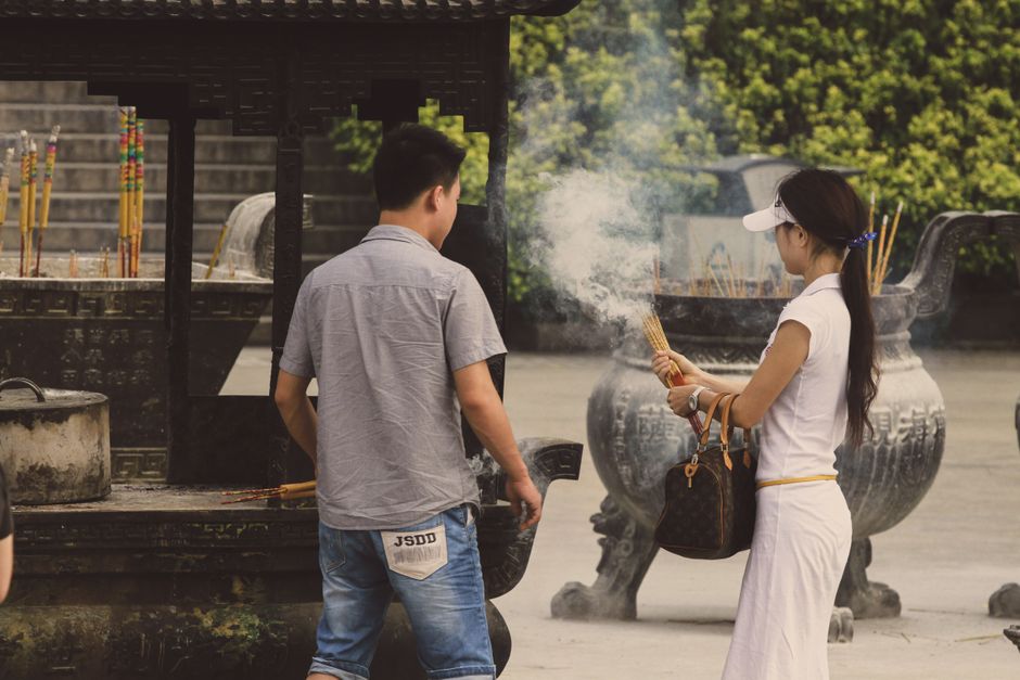 Man and woman performing a traditional incense ritual in an outdoor setting.