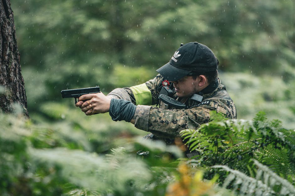 A soldier in camouflage aims a pistol among ferns during rainfall, capturing a military adventure scene.