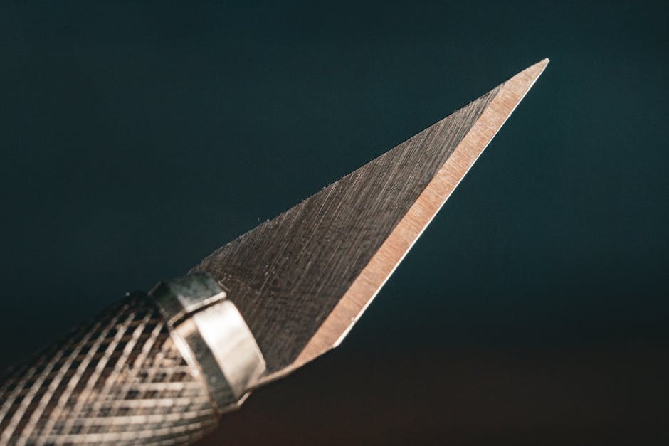 Detailed close-up image of a sharp craft knife blade with a textured handle, emphasizing precision and craftsmanship.